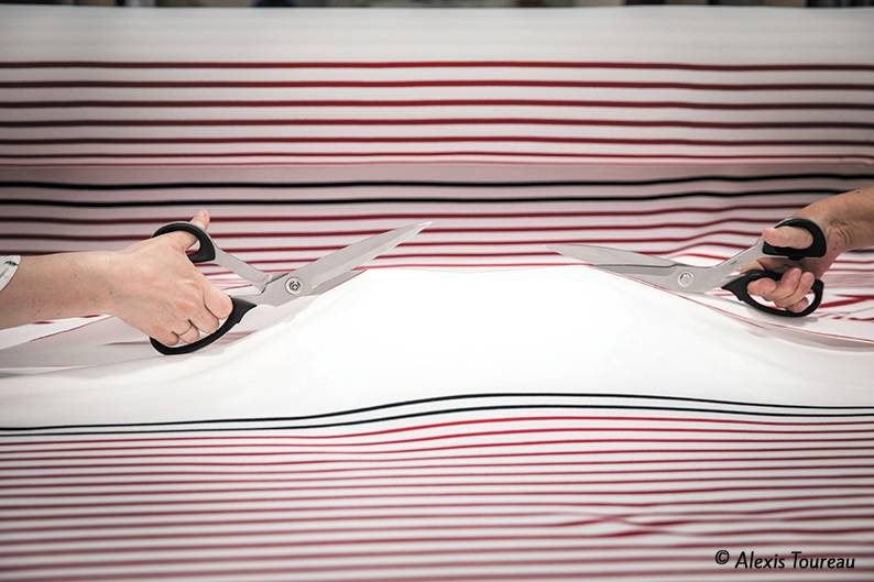 Découpe d’un tissu rayé dans un atelier